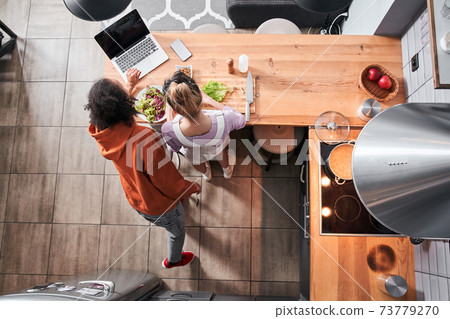 Woman looking at the recipe at the laptop at kitchen Woman looking at the recipe at the laptop at kitchen 73779270