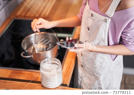 Woman looking recipe at her smartphone while cooking 73779311