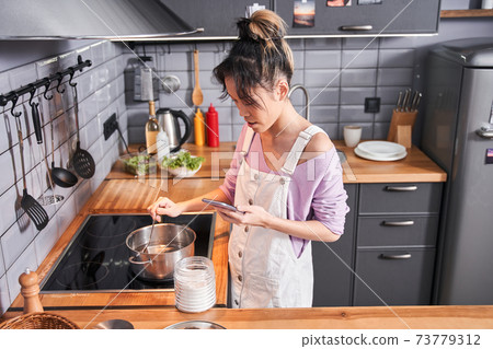 Woman looking at the recipe at her smartphone 73779312