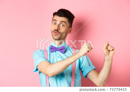 Image of funny guy dancing and celebrating holiday, enjoying party, standing over pink background 73779455