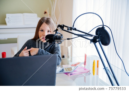 Blogger girl recording video broadcast with microphone about new cosmetic products. Blogger girl recording video broadcast with microphone about new cosmetic products. 73779533