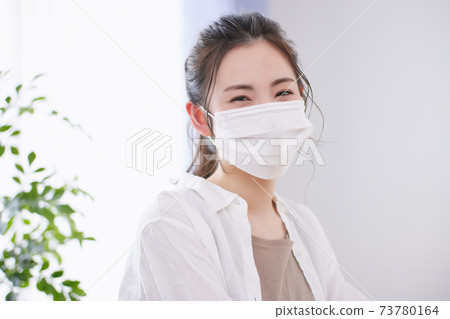 Young woman wearing a mask in the living room 73780164