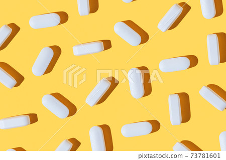 Modern pattern with hard shadows of white pills on yellow background. Food supplement, multivitamins, medications. 73781601