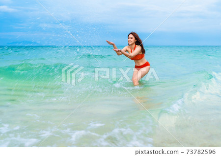 cheerful woman playing water splash in the sea beach at Koh MunNork Island, Rayong, Thailand cheerful woman playing water splash in the sea beach at Koh MunNork Island, Rayong, Thailand 73782596