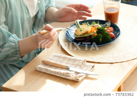 Hands of women eating vegetable dishes 73783362