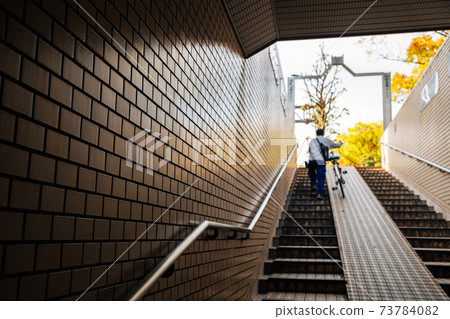 Man climbing stairs with bicycle in Japan Man climbing stairs with bicycle in Japan 73784082
