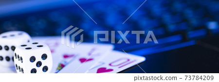Online gaming platform, casino and gambling business. Cards and dice on laptop keyboard, toned in blue Online gaming platform, casino and gambling business. Cards and dice on laptop keyboard, toned in blue 73784209