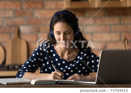 Young Caucasian woman in headphones study online at home Young Caucasian woman in headphones study online at home 73784423