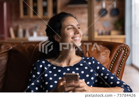 Happy woman use cellphone look in distance dreaming 73784426