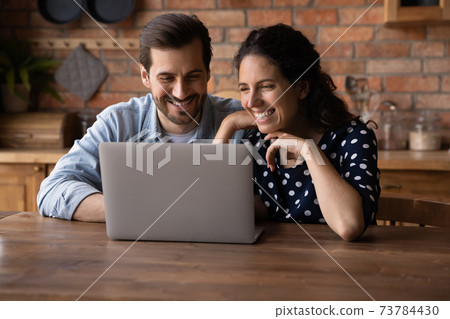 Smiling couple use laptop talking on video call Smiling couple use laptop talking on video call 73784430