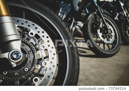 自行車前照燈映照在a-2膠片式自行車停放處排列的自行車前輪上 自行車前照燈映照在a-2膠片式自行車停放處排列的自行車前輪上 73784524