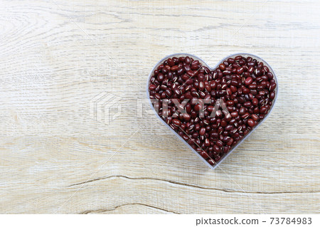 Fresh red bean in a heart shaped mold rests on a wooden table and has a copy space. Fresh red bean in a heart shaped mold rests on a wooden table and has a copy space. 73784983