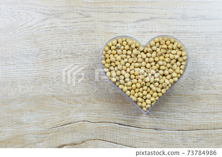 Fresh soybean in a heart shaped mold rests on a wooden table and has a copy space. Fresh soybean in a heart shaped mold rests on a wooden table and has a copy space. 73784986