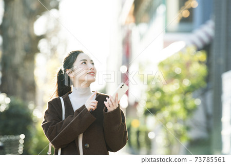 尋找在她的智能手機上一個年輕女子目的地 尋找在她的智能手機上一個年輕女子目的地 73785561