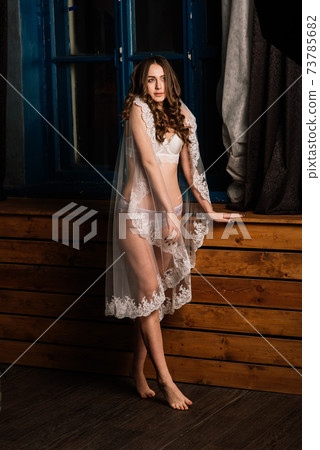 Morning of the bride. Portrait of a beautiful young female in a white underwear. 73785682