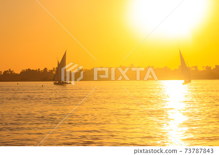 View of the Nile river with sailboats at sunset in Luxor, Egypt View of the Nile river with sailboats at sunset in Luxor, Egypt 73787843
