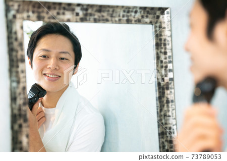 一個人看著鏡子裡的剃須刀剃須 一個人看著鏡子裡的剃須刀剃須 73789053
