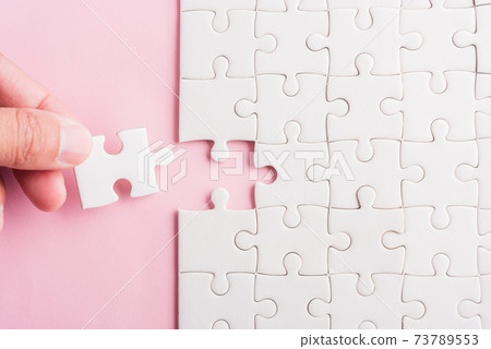 hand-holding last piece white paper jigsaw puzzle game last pieces 73789553