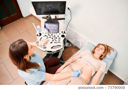 Female doctor examining woman with ultrasound scanner. 73790008