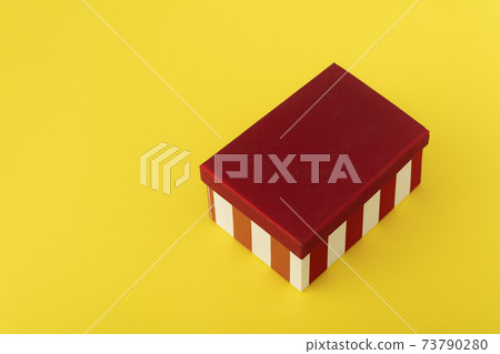 Gift box with red lid on yellow background. Festive packaging. Gift box with red lid on yellow background. Festive packaging. 73790280