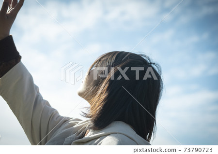 Portrait of a woman feeling the light under the blue sky 73790723