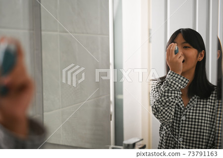 Asthmatic young girl using an asthma inhaler during asthma attacks in toilet at home. Asthmatic young girl using an asthma inhaler during asthma attacks in toilet at home. 73791163