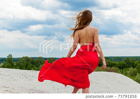 Girl in red cloth on the sand posing 73791858