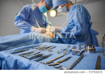 Doctors doing plastic surgery in operating room with medical instruments. Doctors doing plastic surgery in operating room with medical instruments. 73793835