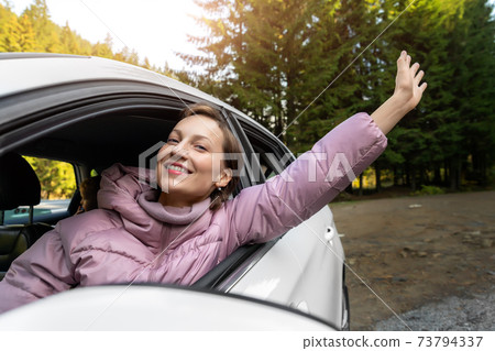 Portrait of young adult beautiful caucasian woman driver enjoy roadtrip adventure traveling by car on mountain nature forest landscape. Happy female person family journey trip lifestyle Portrait of young adult beautiful caucasian woman driver enjoy roadtrip adventure traveling by car on mountain nature forest landscape. Happy female person family journey trip lifestyle 73794337