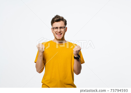 Casual man winning and celebrating handsome young man with hands lifted up. Young casual man portrait isolated on white background. Human emotions, facial expression concept Casual man winning and celebrating handsome young man with hands lifted up. Young casual man portrait isolated on white background. Human emotions, facial expression concept 73794593