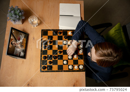 Little Caucasian boy chess player playing chess online using laptop. Little Caucasian boy chess player playing chess online using laptop. 73795024