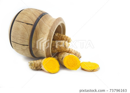 Turmeric roots and a small wooden pot Turmeric roots and a small wooden pot 73796163