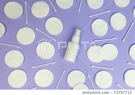 Unbranded white plastic spray bottle mockup and cotton pads pattern on purple background. Top view, flatlay, lifestyle. Clean beauty and liquid antimicrobial spray concept. 73797713