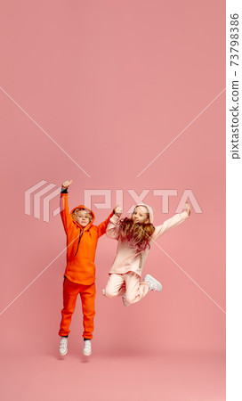 Happy children isolated on coral pink studio background. Look happy, cheerful, sincere. Copyspace. Childhood, education, emotions concept 73798386