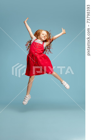 Happy redhair girl isolated on blue studio background. Looks happy, cheerful, sincere. Copyspace. Childhood, education, emotions concept 73798393
