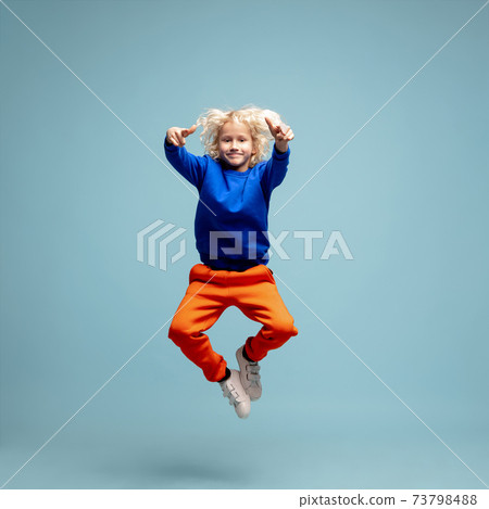 Happy curly boy isolated on blue studio background. Looks happy, cheerful, sincere. Copyspace. Childhood, education, emotions concept Happy curly boy isolated on blue studio background. Looks happy, cheerful, sincere. Copyspace. Childhood, education, emotions concept 73798488