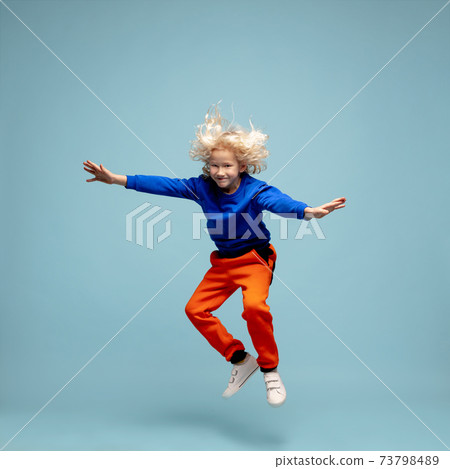 Happy curly boy isolated on blue studio background. Looks happy, cheerful, sincere. Copyspace. Childhood, education, emotions concept Happy curly boy isolated on blue studio background. Looks happy, cheerful, sincere. Copyspace. Childhood, education, emotions concept 73798489
