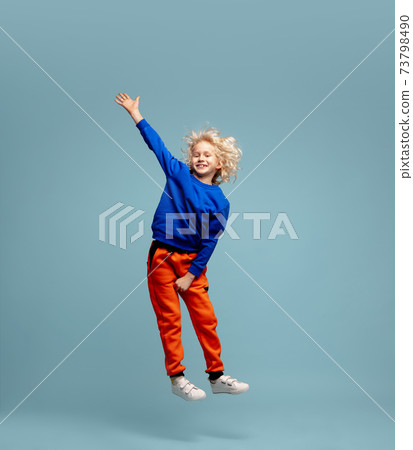 Happy curly boy isolated on blue studio background. Looks happy, cheerful, sincere. Copyspace. Childhood, education, emotions concept Happy curly boy isolated on blue studio background. Looks happy, cheerful, sincere. Copyspace. Childhood, education, emotions concept 73798490