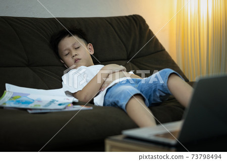 Online education for kindergarteners, kid boy student is sleeping on the sofa while studying online,learning online with laptop computer at home during the pandemic of Coronavirus Covid-19,stay home Online education for kindergarteners, kid boy student is sleeping on the sofa while studying online,learning online with laptop computer at home during the pandemic of Coronavirus Covid-19,stay home 73798494