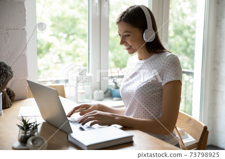 Millennial female studying working online using laptop and wireless headphones 73798925