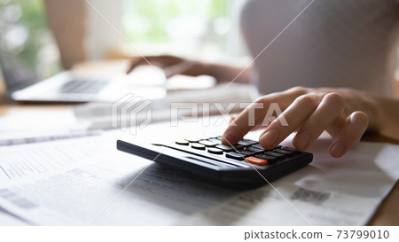 Young female hand counting on electronic calculator planning family budget 73799010