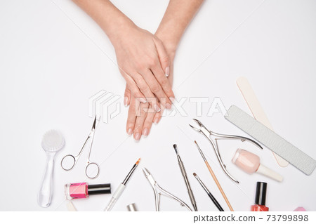top view of manicure tools set for nail care over light background - brush, scissors, nail polish, file and tweezers top view of manicure tools set for nail care over light background - brush, scissors, nail polish, file and tweezers 73799898