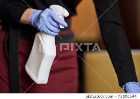 Hard-working crew desinfecting frequently touched areas with sanitizer 73800544