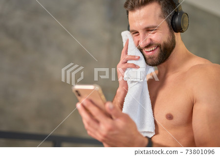 Cheerful young man using modern smartphone after workout 73801096