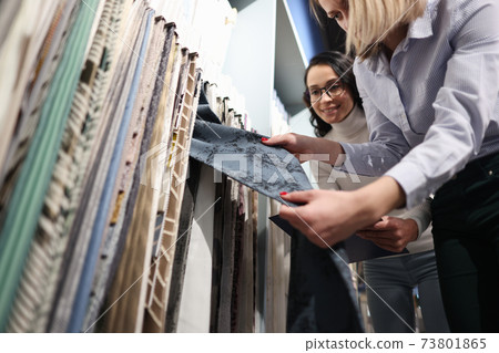 Seller demonstrates fabric samples to client closeup 73801865