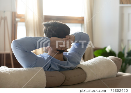 Close up rear view calm man resting on couch 73802430