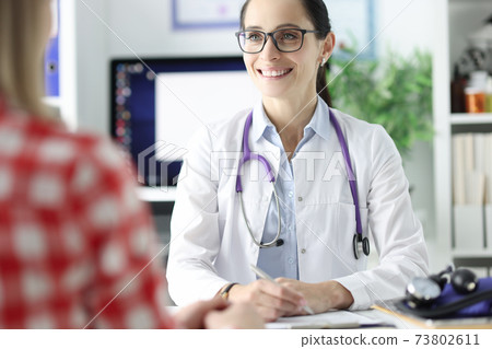 Smiling portrait of doctor in glasses conducts an appointment with patient 73802611