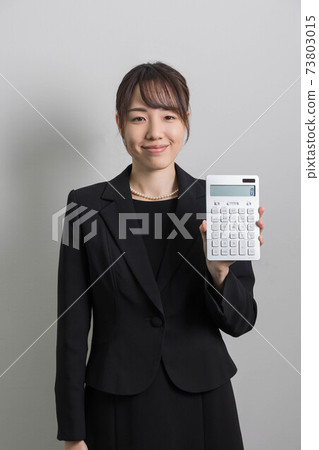 一個年輕的女人，穿著哀悼的衣服，站著一個計算器[葬禮] 73803015