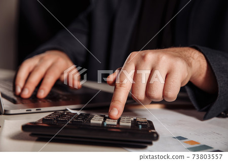 Man working in office using calculator. Close-up. Business concept Man working in office using calculator. Close-up. Business concept 73803557