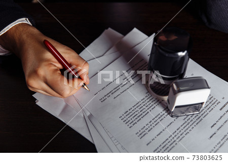 Man sign documents in the office. Stamp and contract on desk Man sign documents in the office. Stamp and contract on desk 73803625